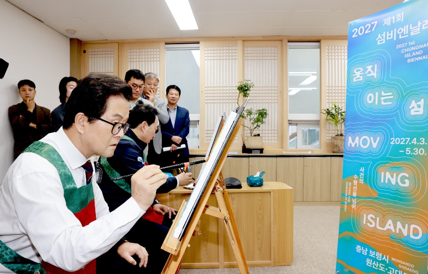 섬비엔날레 안내 배너 옆에서 참가자가 그림을 그리고 있다. 10월 13일 제공 사진. (사진제공=보령시)